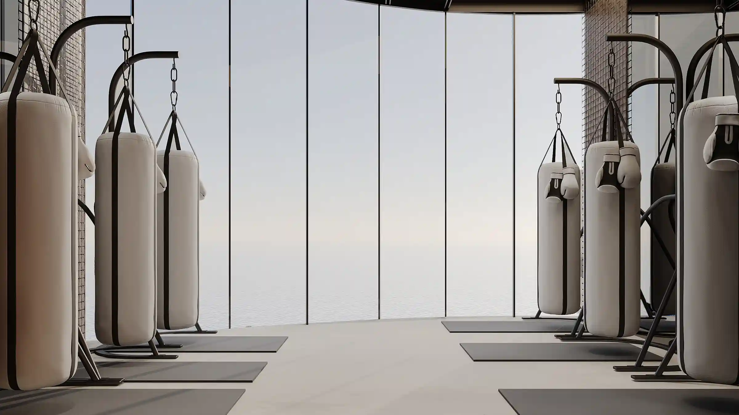 A dedicated boxing and conditioning room featuring premium punching bags and a minimalist, oceanfront backdrop.