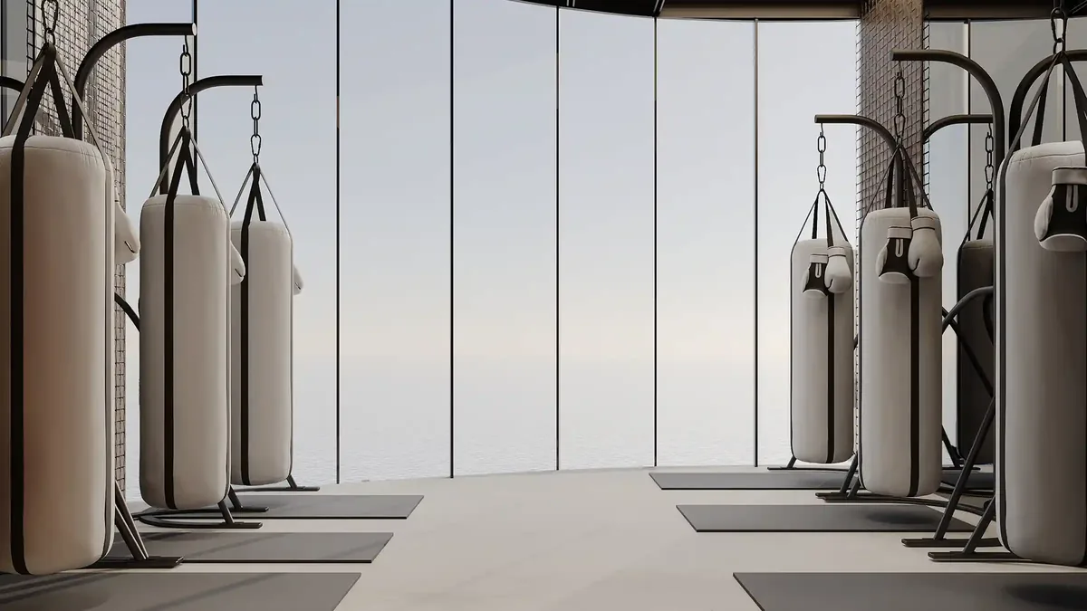 A dedicated boxing and conditioning room featuring premium punching bags and a minimalist, oceanfront backdrop.
